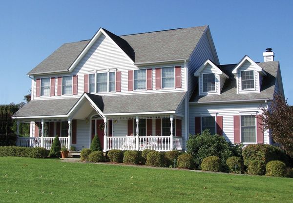 Large white two-story house with red shutters and a green lawn.