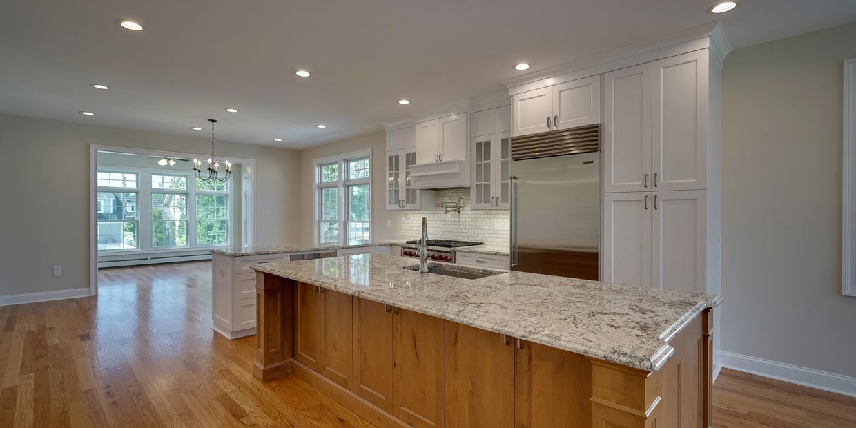 Spacious modern kitchen with granite island and hardwood floors.