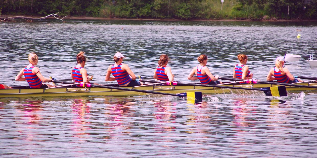 a team rowing in unison, in the water