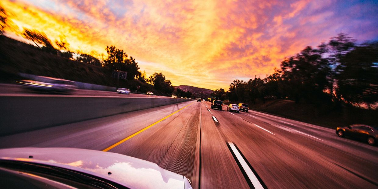 a drivers view, a sunset, cars around on the high-way