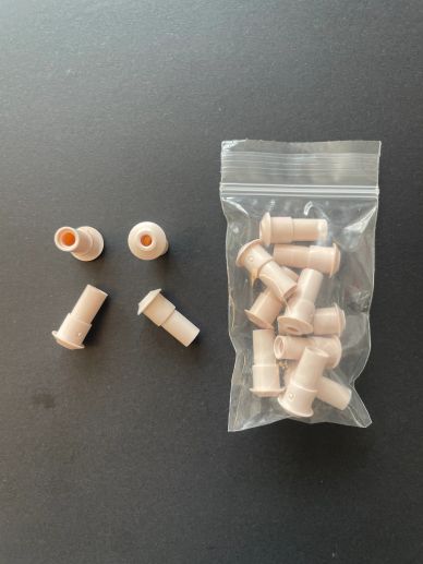 Small beige plastic tube connectors, some loose and some in a plastic bag.