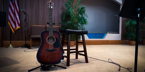 Acoustic guitar and stool on a stage.