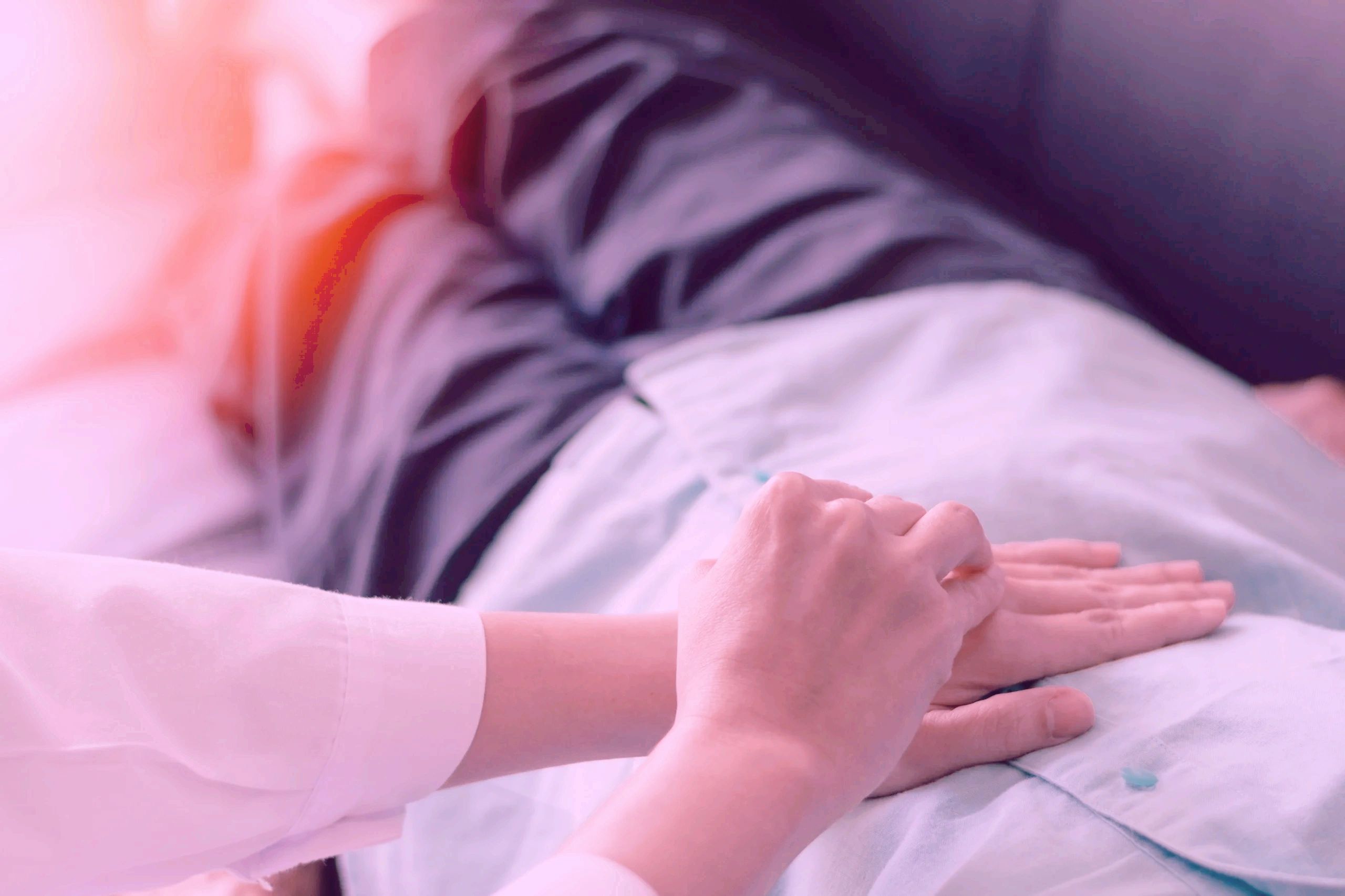 Nurse with hands on client's abdomen over clothes.