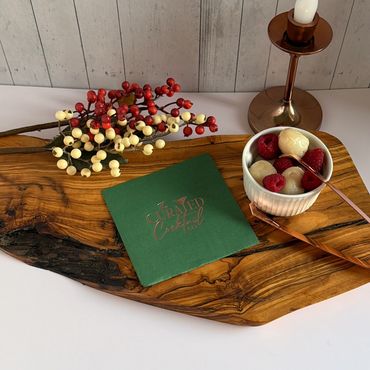 Elegant cocktail setup with berries, a candle, and a wooden board.