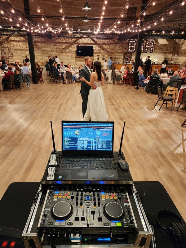 A couple shares their first dance at a wedding with guests seated around the dance floor.