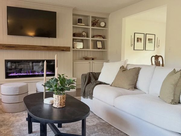 Cozy living room with white sofa, black coffee table, and modern fireplace.
