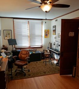 Cozy home office with wooden furniture and natural light from a large window.