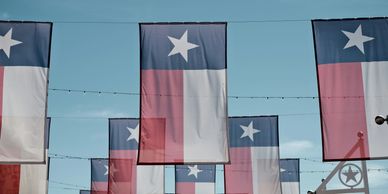 Multiple Texas flags hanging against a clear sky.