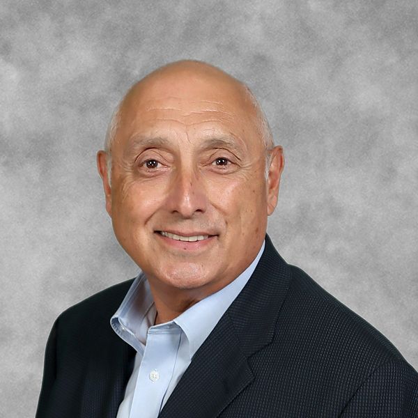 Smiling bald man in suit jacket against grey background.