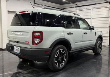 White Ford Bronco Sport parked indoors with black and silver wheels.