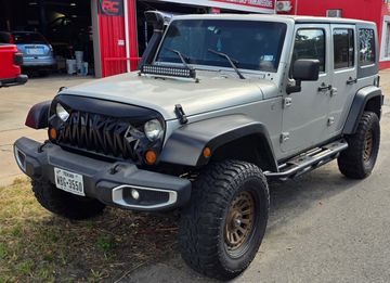 Silver Jeep Wrangler with off-road modifications.