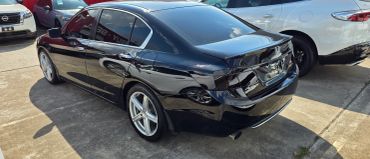 Black sedan parked outdoors beside white car.