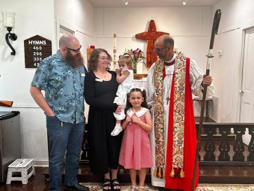 Family with a priest inside a church during a ceremony.