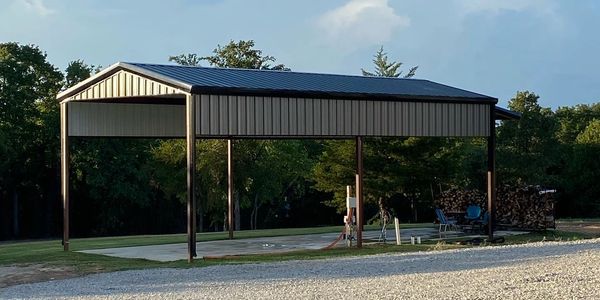 A metal carport structure on a concrete slab with trees in the background.