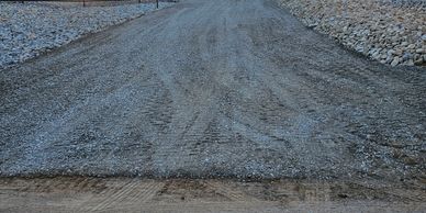 Gravel driveway leads to a gated entrance with flags at sunset.