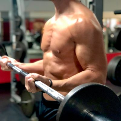 Muscular man performing barbell curls in the gym.