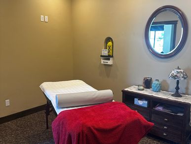 Cozy massage room with a red blanket and decorative mirror.
