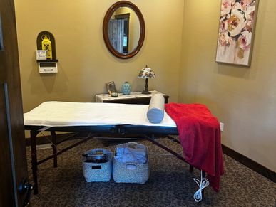 Cozy massage room with a treatment table and decorative accents.