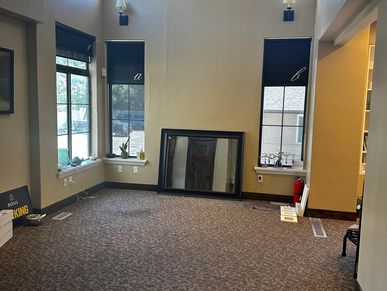 Empty room with carpet, two windows, and a large mirror leaning on the wall.