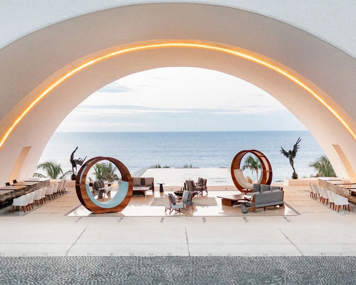 Modern open-air lounge with ocean view and artistic sculptures.