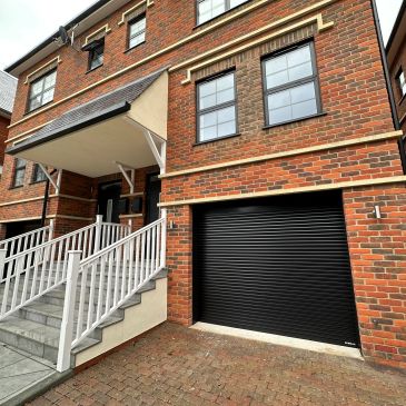Brick townhouse with black garage door and white stair railing.