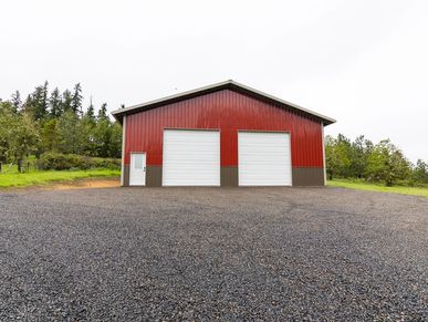 Red metal building with two large garage doors and a small side door.