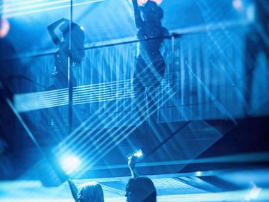 Blue-toned dance performance with audience filming on phones.