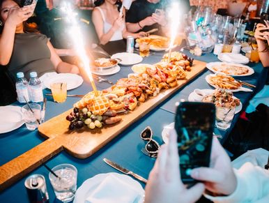 Group enjoying a celebratory meal with a long platter and sparklers.