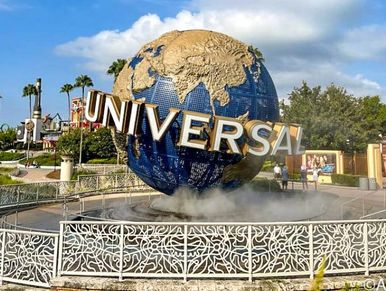 Iconic Universal Studios globe with palm trees and clear sky.