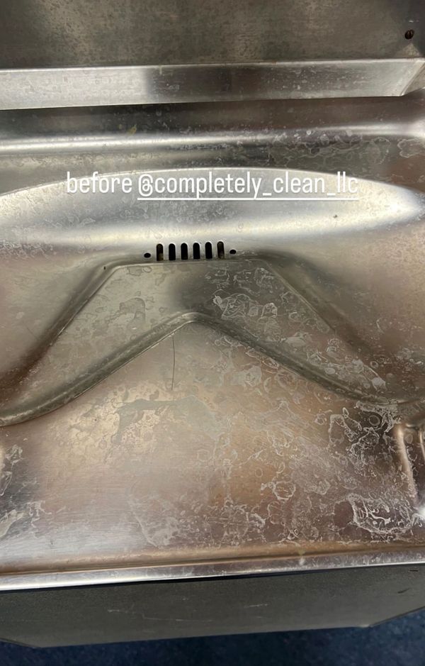 A heavily stained and dirty stainless steel sink before cleaning.