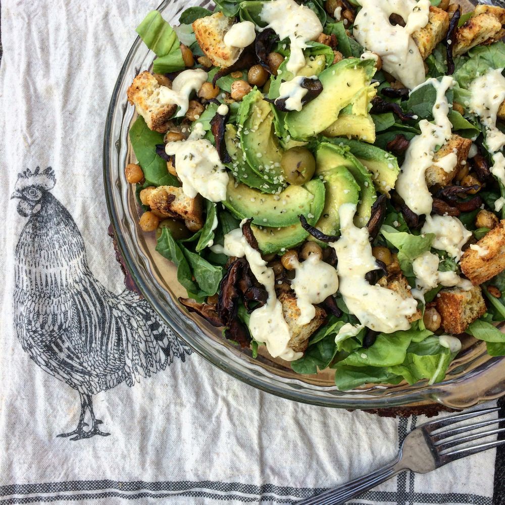 Fresh salad with avocado, chickpeas, greens, croutons, and creamy dressing.