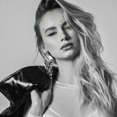 Black-and-white portrait of a woman with decorative face jewels and a leather jacket.