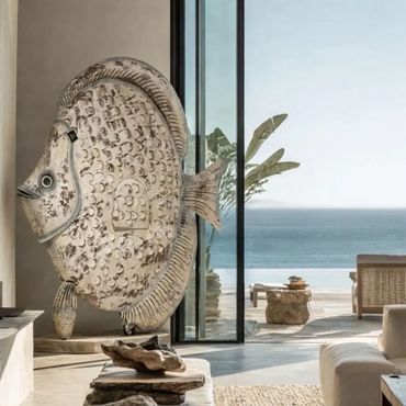 Large decorative fish sculpture in a modern living room with ocean view.