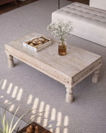 Rustic wooden coffee table with magazine and flower vase in cozy living room.