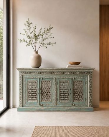 Elegant vintage console with carved doors and a vase with greenery.