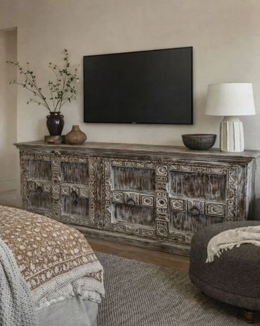 Rustic TV console with decorative carvings under a wall-mounted flat screen.