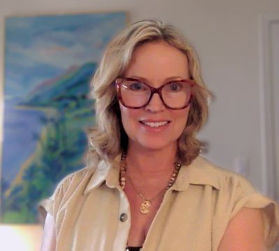 Smiling woman with glasses and shoulder-length blonde hair.