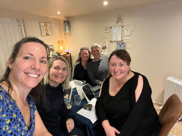 Group of five women smiling indoors.