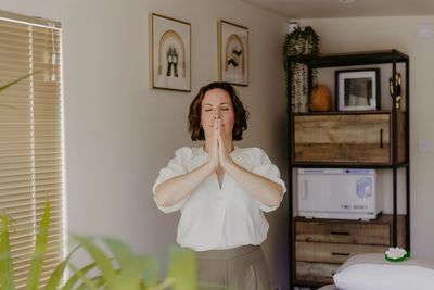 Woman meditating indoors with eyes closed.