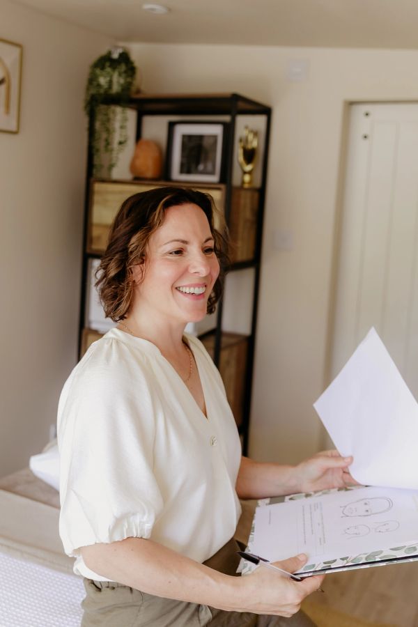 Woman smiling while holding papers indoors.