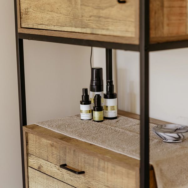 Skincare bottles on a towel-covered wooden shelf.