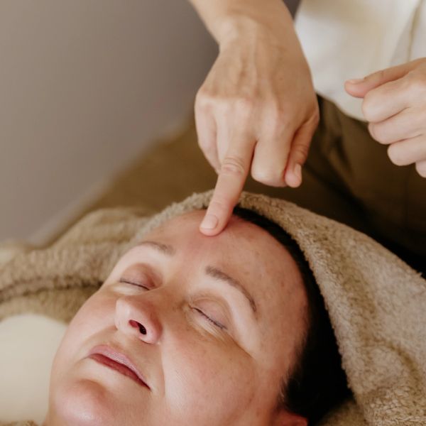 Person receiving a forehead massage with eyes closed.