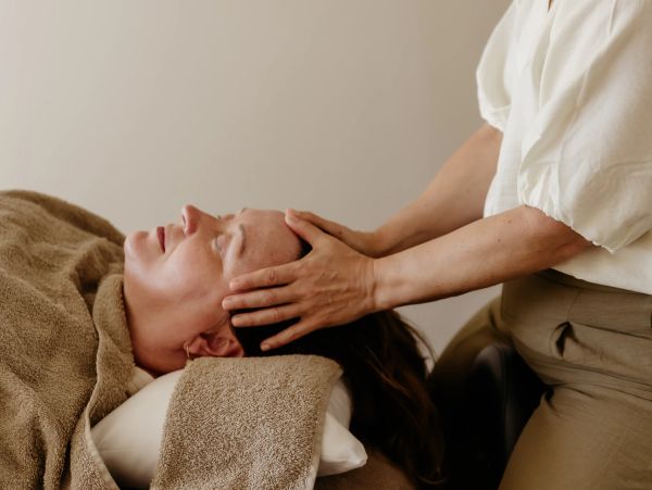 Woman receiving a head massage while lying down.