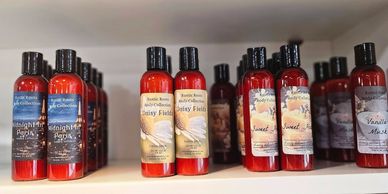 Rows of red bottles with various scented lotion labels on a shelf.