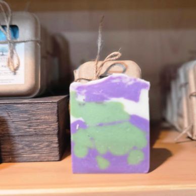 Colorful handmade soap bar with green, purple, and white swirls tied with twine.