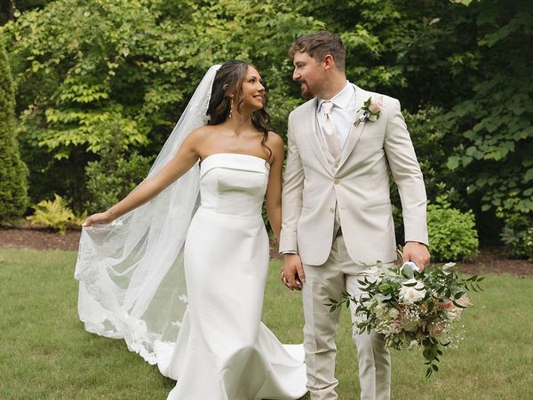 Bride and groom smiling at each other outdoors.