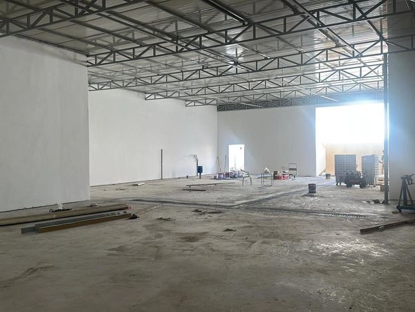 Large empty warehouse under construction with scattered materials.