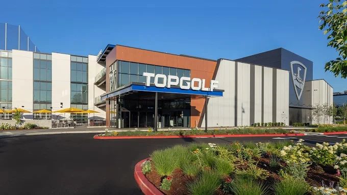 Exterior view of a modern Topgolf building on a clear day.