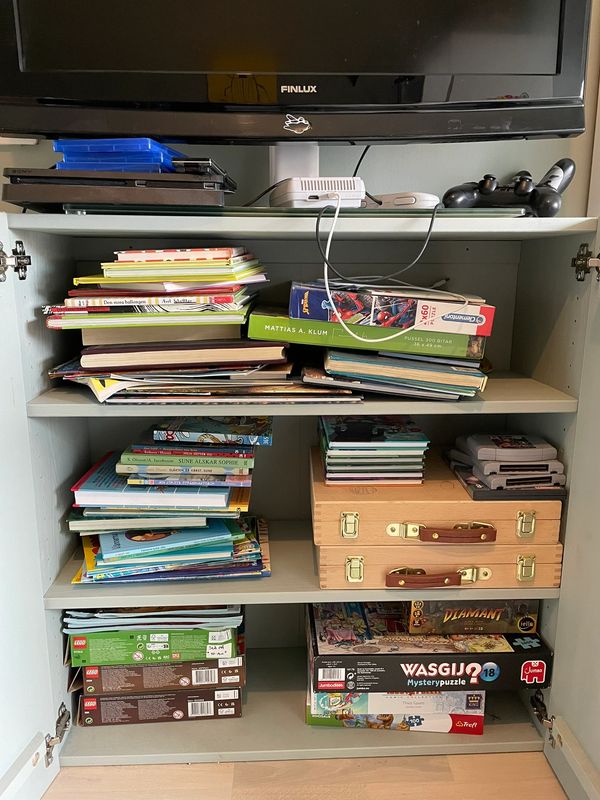 Stökigt skåp i barnrum med spel och böcker. 