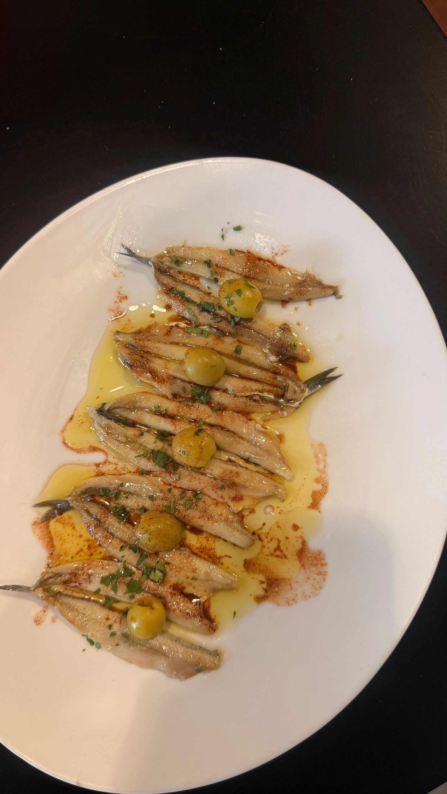 Anchoas con aceitunas y aceite de oliva en un plato.